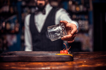 Bearded tapster demonstrates the process of making a cocktail behind bar