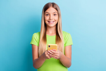 Photo of young smiling happy cheerful good mood girl browsing online in social network isolated on blue color background