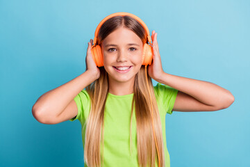 Photo of young cheerful positive good mood smiling girl wearing orange headphones listen music isolated on blue color background