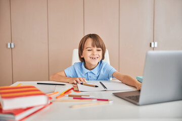Funny kid happy to meet his classmates at the video chat