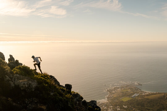 A silhouette of a trail runner running up a steep mountain at sunset