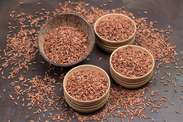 Red brown rice in wooden bowls and coconut shells