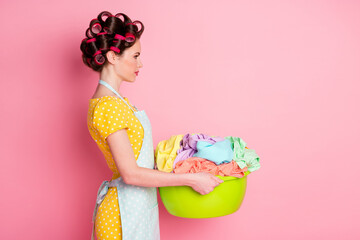 Profile side photo of serious maid girl hold basin dirty clothes look copyspace wear yellow skirt isolated pink color background - Powered by Adobe