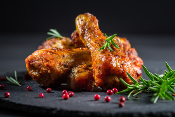 Hot spicy chicken legs with herbs on black background