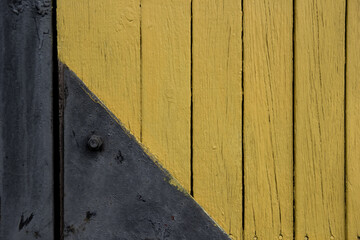 Fototapeta na wymiar Background Wood Texture with black door hinge. Old yellow painted planks. Detail of hinge on old wooden door