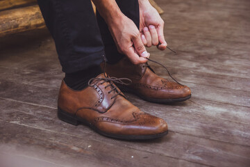 a groom and wedding shoes. Groom is wearing shoes outdoors. Male portrait of handsome guy. Beautiful model boy in colorful wedding clothes. Man is posing.