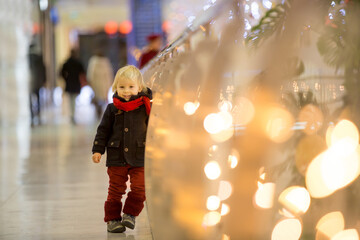 Fashion toddler boy in the city center shopping mall on Christmas