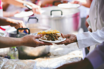 Volunteers scooping the food to share with the needy : concept of free food to beggars