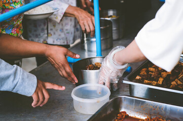 Volunteers scooping the food to share with the needy : concept of free food to beggars
