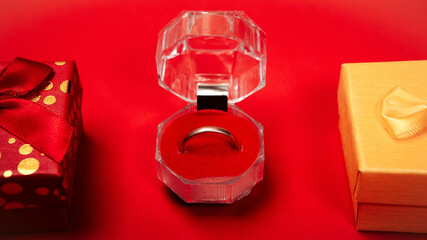 Colorful gift boxes bow presents, golden bright wedding ring marriage proposal on red background. Concept for lover in Valentine's Day, Birthday, New Year or Christmas. Proposing to his girlfriend.