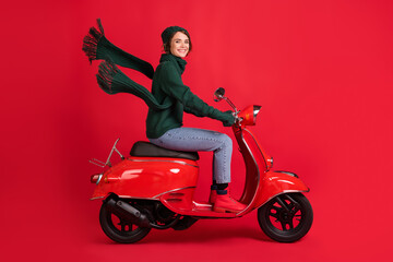 Obraz na płótnie Canvas Side profile full length portrait of attractive person drive moped x-mas trip jeans boots isolated on red color background