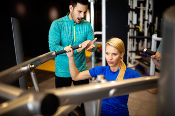 Fototapeta na wymiar Woman with her personal fitness trainer in the gym exercising