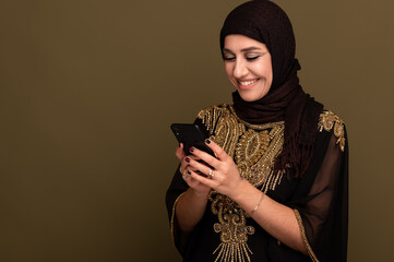 Muslim woman laughing holding her smartphone in hand and taking selfie