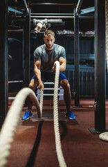 Happy fit men with battle ropes exercise in the fitness gym - obrazy, fototapety, plakaty