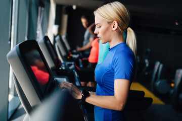 Fototapeta premium Group of young people running on treadmills in sport gym