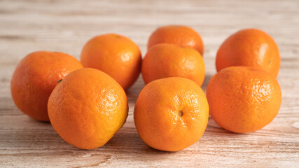Scattered clementines, tangerines, mandarins, oranges on bright wooden background. Winter vitamin C