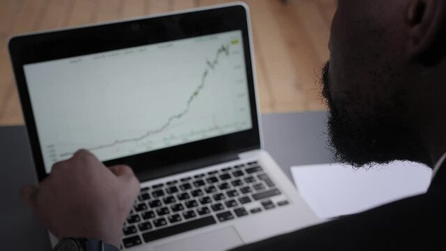 Young businessman analyzes the financial graph on a laptop in the office. stock market trading