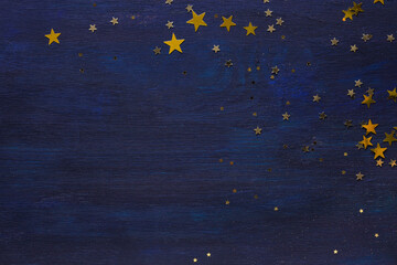 Dark-blue wooden background with golden stars.  Flat lay. - obrazy, fototapety, plakaty