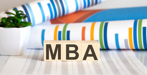 MBA written on a wooden cube in front of a charts