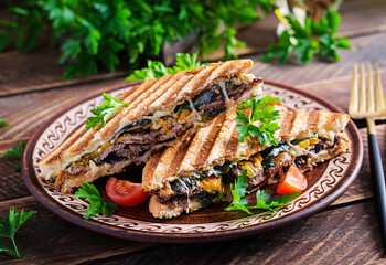 Grilled club sandwich panini with beaf, tomato, cheese and leaf mustard. Delicious breakfast or snack.