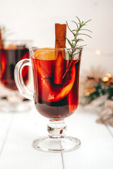 A glass of hot homemade mulled wine with oranges and rosemary in a New Year's atmosphere, vertical photo