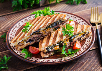 Grilled club sandwich panini with beaf, tomato, cheese and leaf mustard. Delicious breakfast or snack.