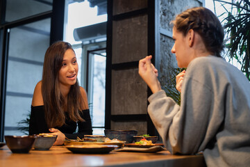 Two young girls chatting in an asian style cafe.