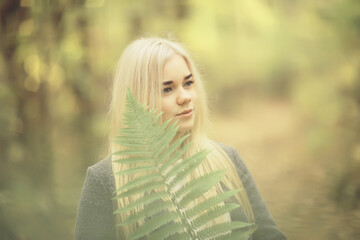 Naklejka premium eco concept girl portrait fern, young adult model blonde, green leaf on face