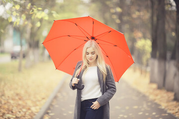autumn look, sunny day a young girl with an umbrella walks in a yellow park in October