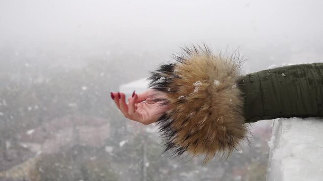 A woman's hand catches large flakes of snow.