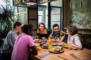 Group of friends sitting and having a meal in a cafe.