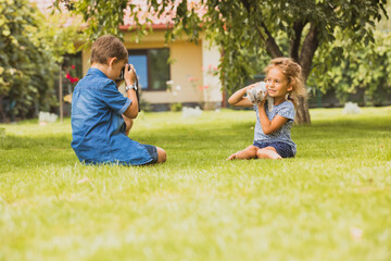 The kids with a kitten are photographed in the backyard