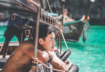 Fototapeta na wymiar an Asian man looking outside a boat on a sightseeing day trip near Phi Phi island, Krabi, Thailand