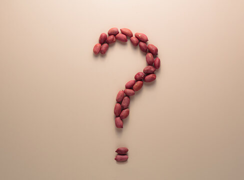 Question mark sign made of peanuts. Top view. Nutrition and food choices. Doubts about the product