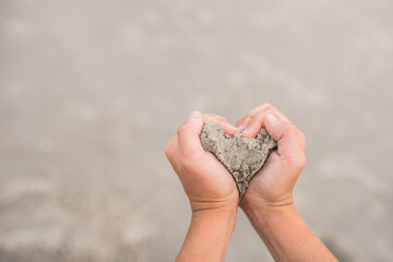 Fototapeta na wymiar heart on beach sand with hands girl 