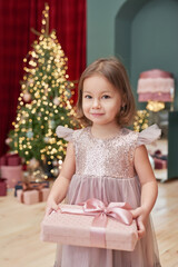Fototapeta na wymiar Christmas baby. Child girl with gifts on background of Christmas tree. Xmas greeting card. Merry christmas background. Happy New Year! Winter celebrations, holidays and vacations.