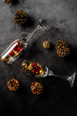 Christmas composition on a dark background with empty champagne glasses and Christmas toys and cones, view from the top