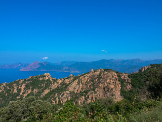 Beautiful view of sunlit red mountains and mediterranean sea in Calanches area on corsica island, near Village Piana