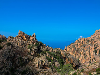 Fototapeta premium Beautiful view of sunlit red mountains and mediterranean sea in Calanches area on corsica island, near Village Piana