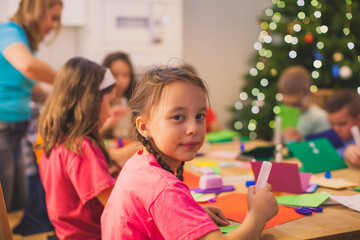 Cheerful girl while Christmas workshop among other kids