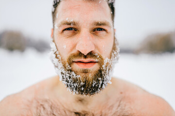 Portrait of strong brutal naked man with frozen beard posing outdoors