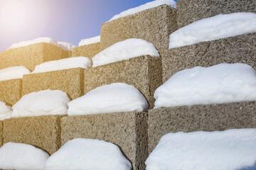 large blocks of arbolite stacked in a stack against a blue sky, foreground and background blurred with bokeh effect