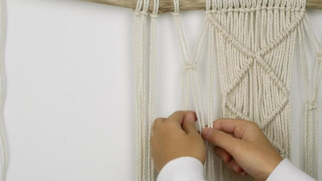 A woman weaves with her own hands a pattern of Macrame threads for decoration or home decor. Home decor idea handmade Macrame cotton.