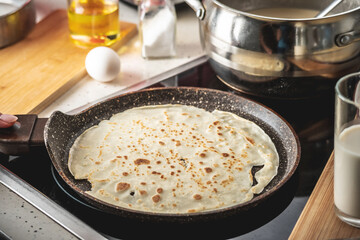 Pancake is cooking in a hot frying pan. Concept of the process of making homemade pancakes in your...
