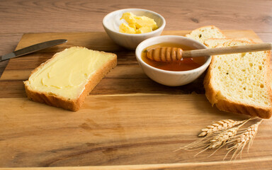 Bread with honey and butter on wooden background
