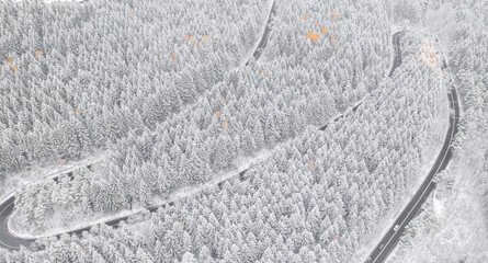 Aerial view of an amazing winding curved road through the mountains in winter snow landscape, motorway in Romania
