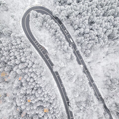 Obraz premium Aerial view of an amazing winding curved road through the mountains in winter snow landscape, motorway in Romania