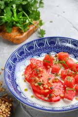 stracciatella salad with tomatoes and watermalone and ingredients on light concrete table