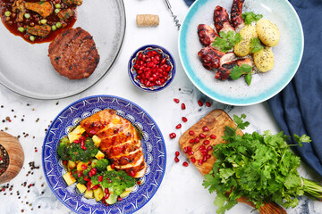 table with meat meal and salad. octopus with potatoes and chicken with mango, meat pattie with peas and ingredients on table top view