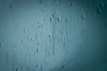 Close up of splashes of water and waterdrops running down on glass panel of bathtub in bathroom...